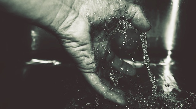 Black and white photograph of water splashing on hand